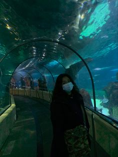 a woman wearing a face mask standing in front of an aquarium