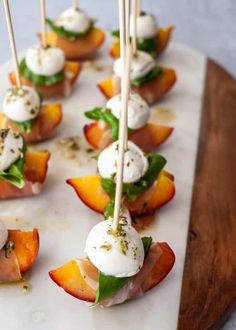 small appetizers are lined up on a cutting board with toothpicks sticking out of them