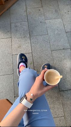 a person sitting on the ground holding a cup of coffee