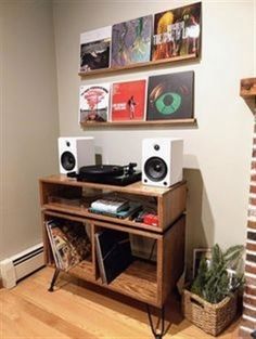 there is a wooden table with speakers on it and pictures above the fireplace in this living room