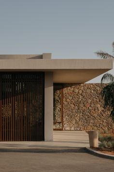 a modern house with stone walls and palm trees