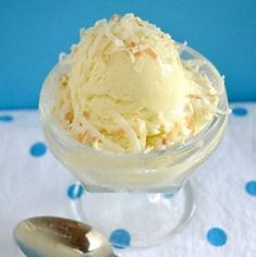 an ice cream sundae in a glass bowl with a spoon on the side and blue polka dot tablecloth