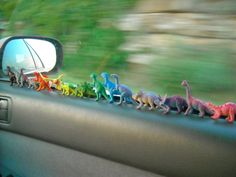 toy dinosaurs are lined up on the dashboard of a car in front of a rear view mirror