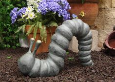 a potted plant sitting on top of a sidewalk next to a flower pot filled with purple and white flowers