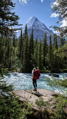 a woman standing on a rock looking at a mountain