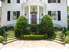 a large white house with black shutters on the front door and steps leading up to it