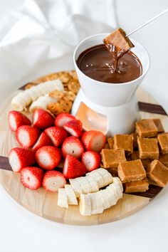 a plate with strawberries, crackers, and chocolate sauce on it next to other snacks