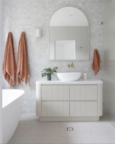 a white bathroom with two sinks and towels hanging on the wall