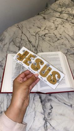 a person is holding an open book with the word jesus in gold letters on it