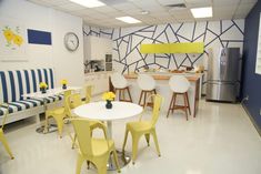 a room with yellow chairs and white tables