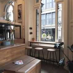 the interior of a restaurant with stools and tables in front of two large windows