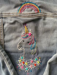 the back pocket of a pair of jeans with embroidered unicorns and flowers on them