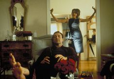 a man sitting in a chair next to a woman with her arms up and legs crossed