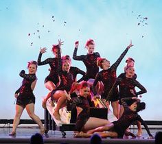 a group of women on stage with their arms in the air and one woman holding her leg up