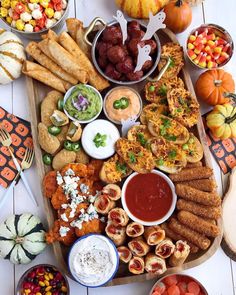 an assortment of food on a wooden platter with pumpkins and other foods around it