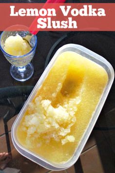 lemon vodka slush in a plastic container next to a glass with ice cream on it