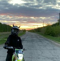 a person on a dirt bike in the middle of an empty road at sunset or dawn