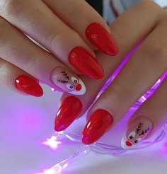 a woman's hand with red nail polish and reindeer face on the tip of her nails