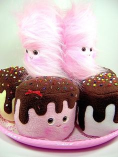 three stuffed toys sitting on top of a plate with frosting and sprinkles