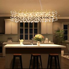 a kitchen island with stools and a chandelier hanging from it's ceiling