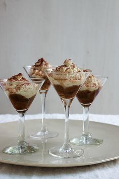 three glasses filled with dessert sitting on top of a white plate