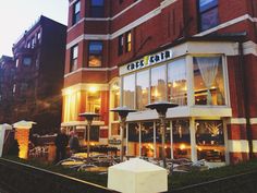 the outside of a restaurant with tables and umbrellas in front of it at night