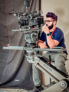 a man sitting in front of a camera on top of a tripod next to a video camera