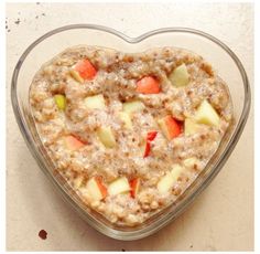 a heart shaped bowl filled with oatmeal and fruit on top of a table