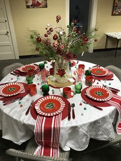 the table is set for christmas dinner with red and green decorations