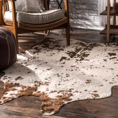 a brown and white cowhide rug in front of a wooden chair with two chairs