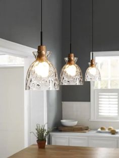 three pendant lights hanging from a kitchen ceiling