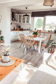 a kitchen and dining room with wood floors, white walls and furniture in the background