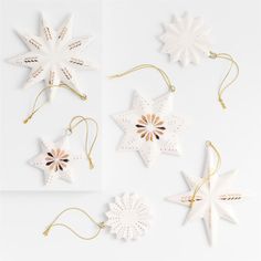 six white and gold christmas ornaments hanging from strings on a white surface, with one star shaped ornament in the middle