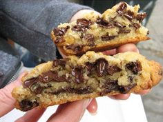 two chocolate chip cookies are being held in someone's hand