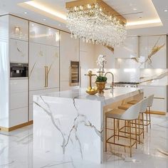 an elegant kitchen with marble counter tops and gold accents on the ceiling, along with white cabinets