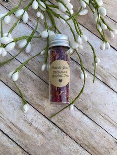 a jar filled with flowers sitting on top of a wooden table