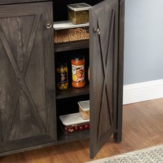 a wooden cabinet with doors open and spices in the bottom drawer, on top of a hard wood floor