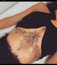 a woman laying on top of a bed with her stomach covered in tattoos