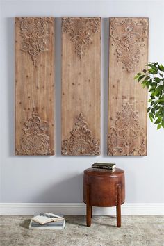 three wooden panels hanging on the wall above a small table with a potted plant