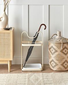 an umbrella is sitting on a stand next to a basket