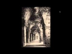 an old black and white photo with trees on either side of the walkway that is lined with arches