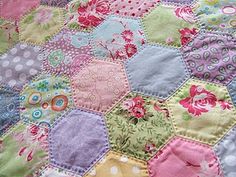 a colorful patchwork quilt is displayed on a bed sheet with polka dots and flowers