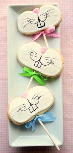 three decorated cookies on a plate with toothpicks