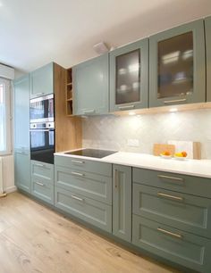 an empty kitchen with green cabinets and white counter tops is seen in this image from the front