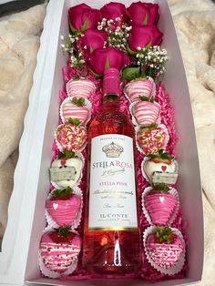 a bottle of pink wine in a box with strawberries and roses on the table