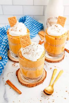 two desserts with graham crackers and whipped cream on top are sitting on wooden coasters