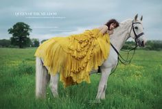 a woman in a yellow dress is sitting on a white horse and posing for the camera