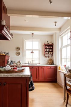 a kitchen with wooden floors and red cabinets