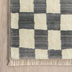 an area rug with black and white checkered squares on the floor, next to a wood floor