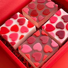 four heart shaped chocolates in a red box with white frosting and pink icing